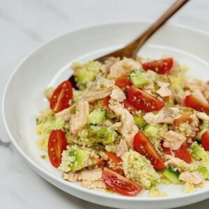 Flaky salmon mixed with fluffy couscous and fresh herbs in a bowl.