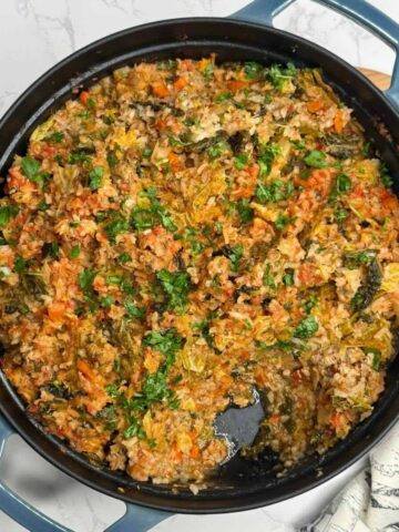 A large skillet filled with a hearty Cabbage Roll Casserole made with ground beef and rice.