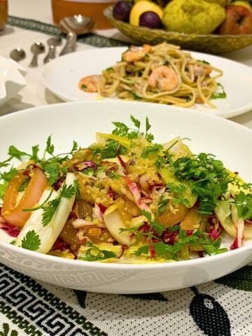 Chicory salad ingredients laid out on marble with clementines pomegranate and fresh chervil.