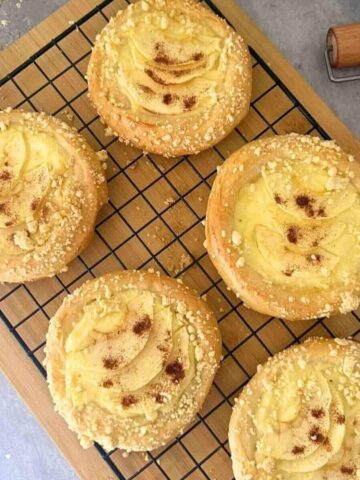 Finished apple custard pastries with powdered sugar on a rack.
