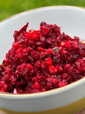 Simple beetroot salad with apple and carrot in a bowl with fresh herbs.