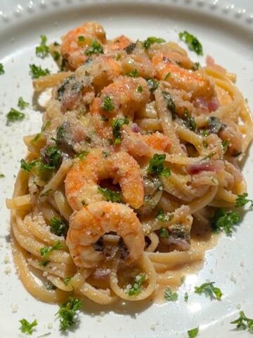 Shrimp linguine with lemon garlic butter plated with parsley garnish.